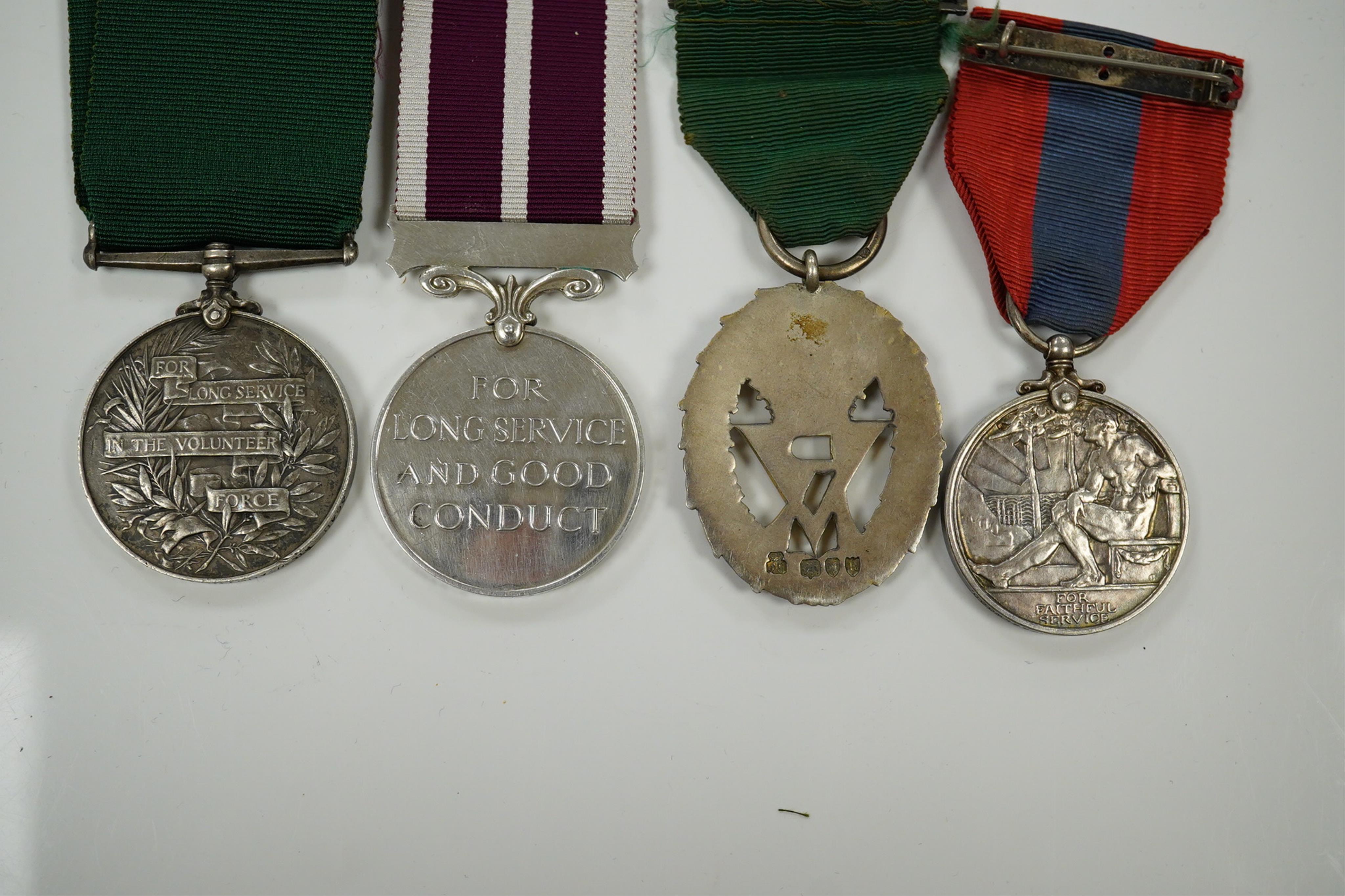 Four assorted service medals; Volunteer Officer's Decoration, hallmarked for 1892; EdVII Volunteer Long Service Medal to 3648 Pte W.Austin I/V B:Lanc:Fus; GV Imperial Service Medal to Frederick Allan Heselwood & Gv Regul